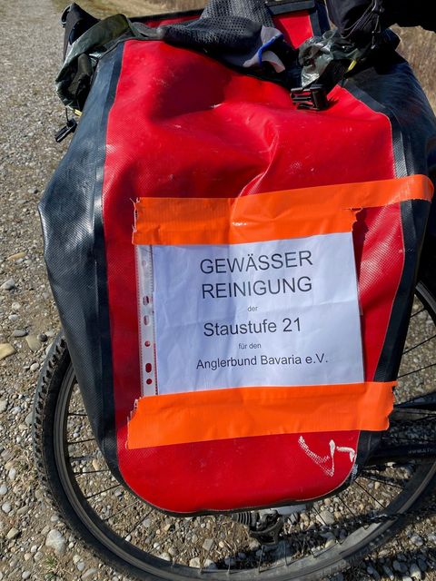 Zu Land per Rad: Satteltasche mit dem Hinweis „Gewässerreinigung Staustufe 21“